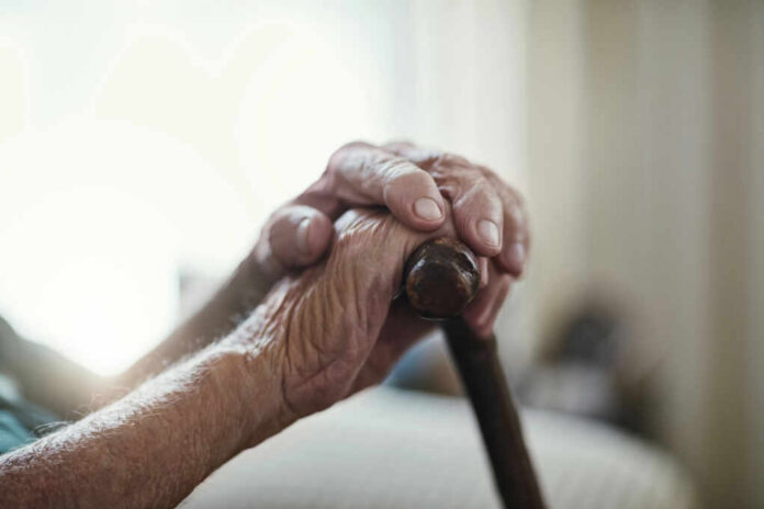 shutterstock2462703011jpg Close-up of elderly hands resting on a cane