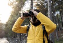Binocular Activities Aid Aging Brains Person in a yellow jacket using binoculars in a forest
