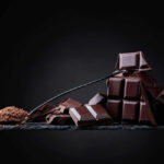 Dark Chocolate’s Hidden Heart-Saving Powers A pile of dark chocolate bars with cocoa powder on a black surface
