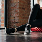 Unlock Hips Fast with This Simple Pose Person using a foam roller for stretching in a fitness studio