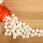 Weight-Loss Drug’s Hidden Double-Edged Sword Spilled white pills from a prescription bottle on a wooden surface
