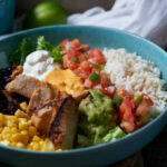 Your Groceries: A Toxic Chemical Mix? A vibrant bowl filled with grilled chicken, rice, black beans, corn, guacamole, and fresh vegetables