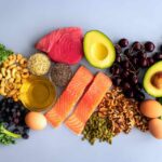 China Study Reveals Vegan Diet Pitfalls An assortment of healthy foods including fish, nuts, fruits, and vegetables arranged on a light background