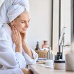 Surprising Skincare Duo Revolutionizes Anti-Aging Woman in a bathrobe with a towel on her head, smiling at her reflection in a mirror