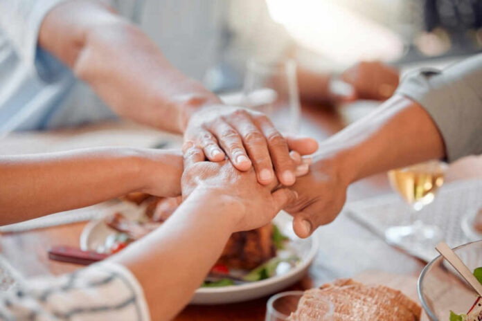 shutterstock_2502384093.jpg Several hands stacked together over a plate of food, symbolizing unity and support