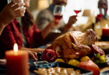 A beautifully roasted turkey surrounded by fruits and candles on a festive dining table