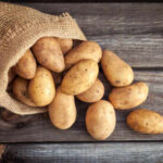 Purple vs. Red: Which Potato Reigns Supreme? A burlap sack spilling fresh potatoes onto a wooden surface