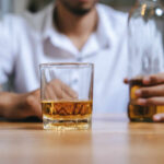 Monthly Drinking Binge: A Hidden Health Threat A man holding a whiskey glass and a bottle in a bar setting