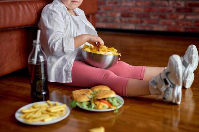 shutterstock_2081601751.jpg Child sitting on the floor enjoying snacks from a bowl