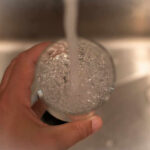 Superbug Breeding Ground in Your Bathroom Sink A hand holding a glass under running water, creating bubbles