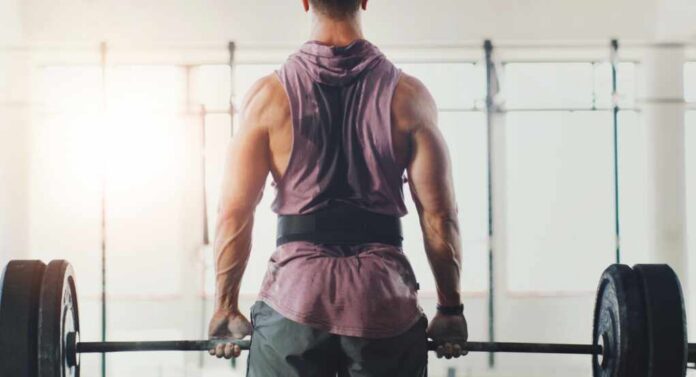 shutterstock_2489917783.jpg A muscular person preparing to lift a barbell in a gym setting