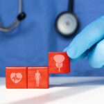 The Aging Organ Nobody Talks About A doctor's gloved hand placing red blocks with health symbols on a table