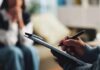 Stress-Busting Habits Experts Swear By A therapist taking notes during a session with a client in the background