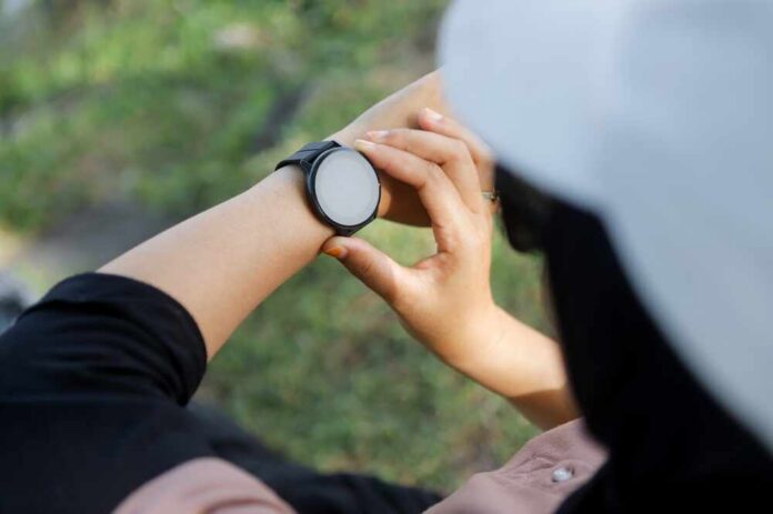 shutterstock_2640951391.jpg Person adjusting a smartwatch on their wrist outdoors