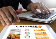The Emotional Trap That Undermines Dieting Person using a calorie counter app on a tablet while working on a laptop