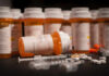 Various prescription medication bottles and syringes on a table