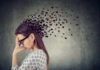 Silent Brain Fog Warnings Most Ignore A woman with glasses holding her head, with fragments dispersing from her head