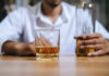 Surprising Link Between Alcohol and Snack Cravings A man holding a whiskey glass and a bottle in a bar setting