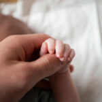 A close-up of a babys hand being held by an adult hand