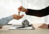 Earthship Homes: What They Are, What They Cost, and Are They’re Worth It? A person handing over house keys during a real estate transaction