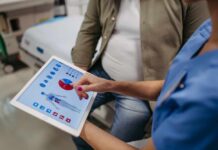 Oncologists Flip Script On Cancer Survivorship Nurse showing a patient health data on a tablet