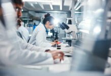 Hidden Weakness Found in ‘Invisible’ Cancer Tumors Scientists working in a laboratory with microscopes and test tubes