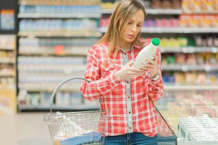 Woman reading a bottle label in a grocery store aisle