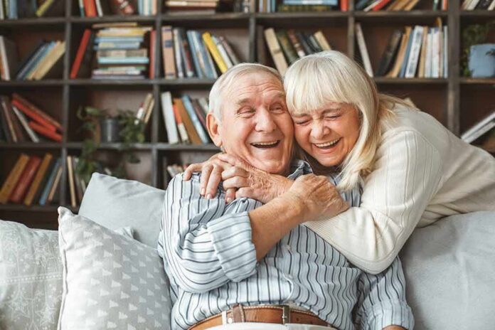 shutterstock_1049436014 Senior couple hugging and laughing on a couch