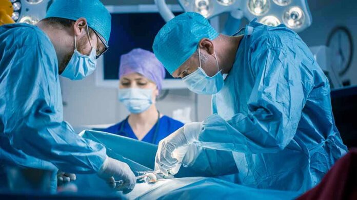 shutterstock_1152711362 Surgeons perform an operation in a hospital operating room