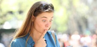 Woman looking surprised at smartphone outdoors