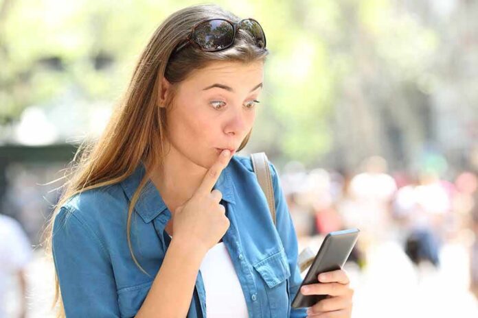 Woman looking surprised at smartphone outdoors