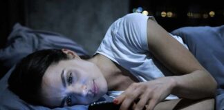 Woman lying in bed looking at a smartphone