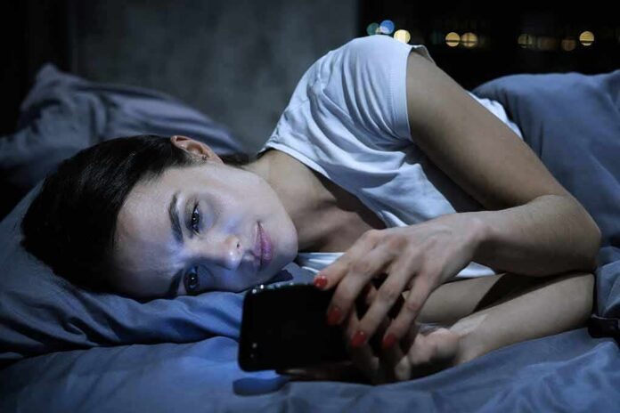 Woman lying in bed looking at a smartphone