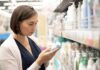 Sunscreen In Blood – What Dermatologists Admit Woman shopping for skincare reading a bottle in a store aisle