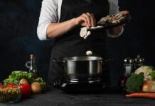 Cook adding sliced mushrooms to a pot
