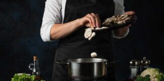 Cook adding sliced mushrooms to a pot