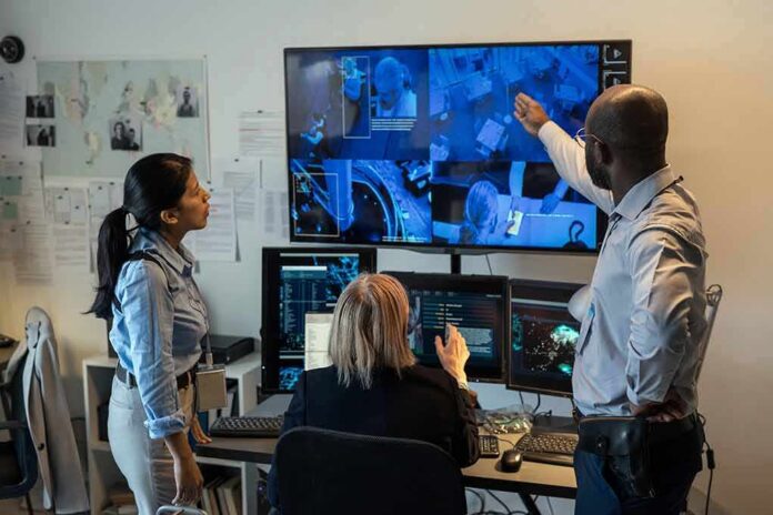 shutterstock_2140269827 Security team monitors multiple surveillance screens in control room