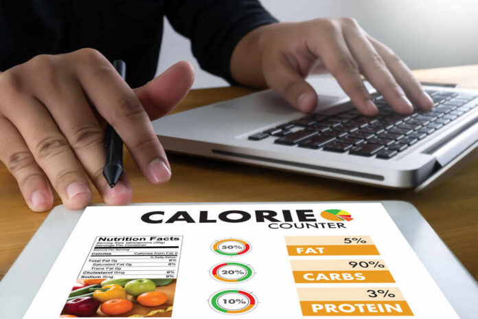 Calorie,Counting,Counter,Application,Medical,Eating,Healthy,Diet,Concept Person using a calorie counter app on a tablet while working on a laptop