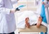 Medical staff stand near a covered body on a gurney with a toe tag