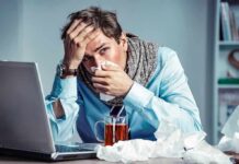 When “Just a Flu” Turns Fatal Sick man at desk blowing his nose