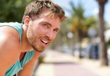 Best Drink For Recovering After A Tough Workout man in athletic tank top resting outdoors