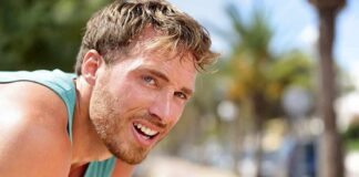 man in athletic tank top resting outdoors
