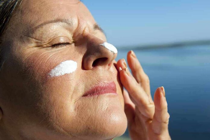 Woman applying sunscreen near water