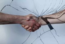 Handshake seen through cracked glass