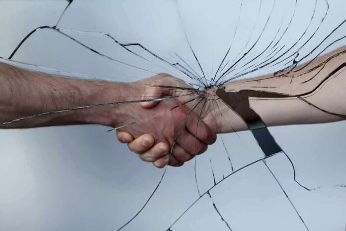 Handshake seen through cracked glass