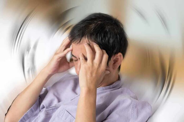 shutterstock_1531691087 Person holding head with spinning blur effect