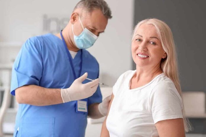 shutterstock_2044901948 Smiling woman receiving a vaccination from a healthcare worker