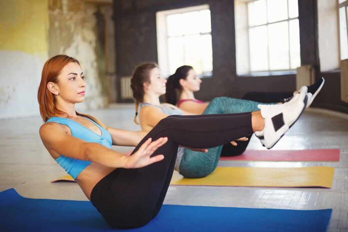1783890187988-luc5z2-shutterstock-1149554819-1 Women practicing boat pose on yoga mats in a studio