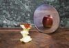 Apple core facing a mirror showing a whole apple