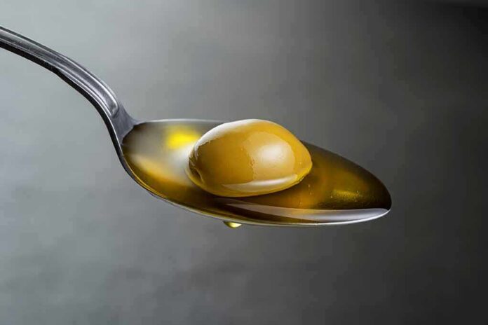 shutterstock_1174374922 Green olive on a spoon with olive oil